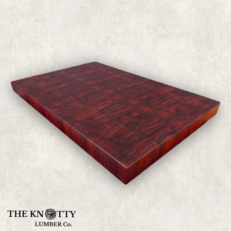 A rectangular Padauk butcher block with a rich red-brown wood grain, edges are smooth and polished.