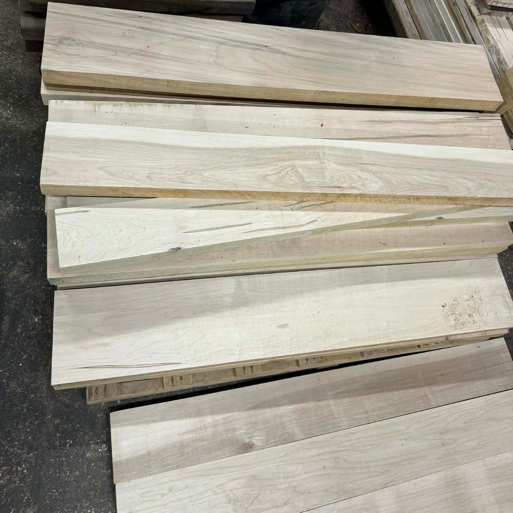 Stack of wooden planks with a black dog peeking from behind them.