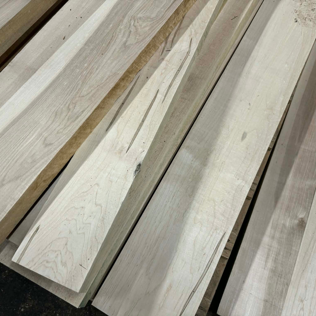 Stack of light-colored wooden planks on a dark surface