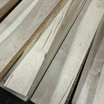 Stack of light-colored wooden planks on a dark surface