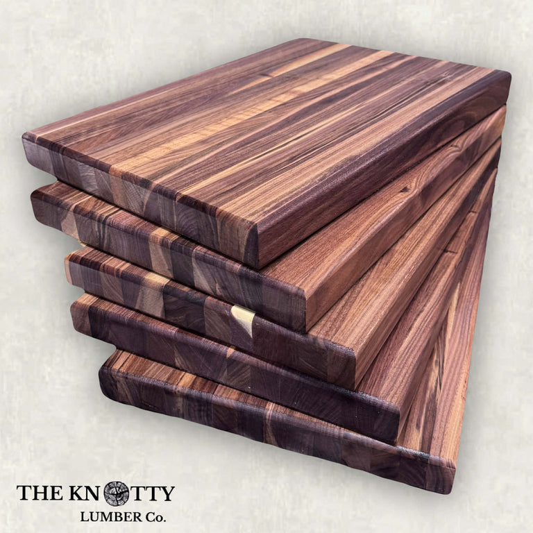 Set of wooden cutting boards stacked on a light gray background with 'The Knotty Lumber Co.' branding.