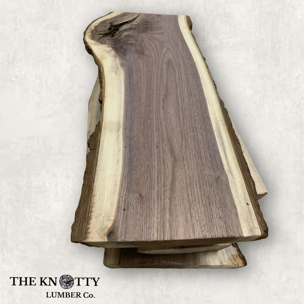 A live edge charcuterie board made of Black Walnut wood, with a rough, natural edge and a mix of light and dark brown tones.