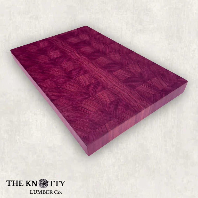 An end grain purpleheart butcher block cutting board with visible wood grain, branded by THE KNOTTY LUMBER CO.