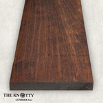 Nogal Wood. Peruvian Walnut 4/4 hardwood image. A Wooden board with the grain and with 'The Knotty Lumber Co.' logo on a light grey background